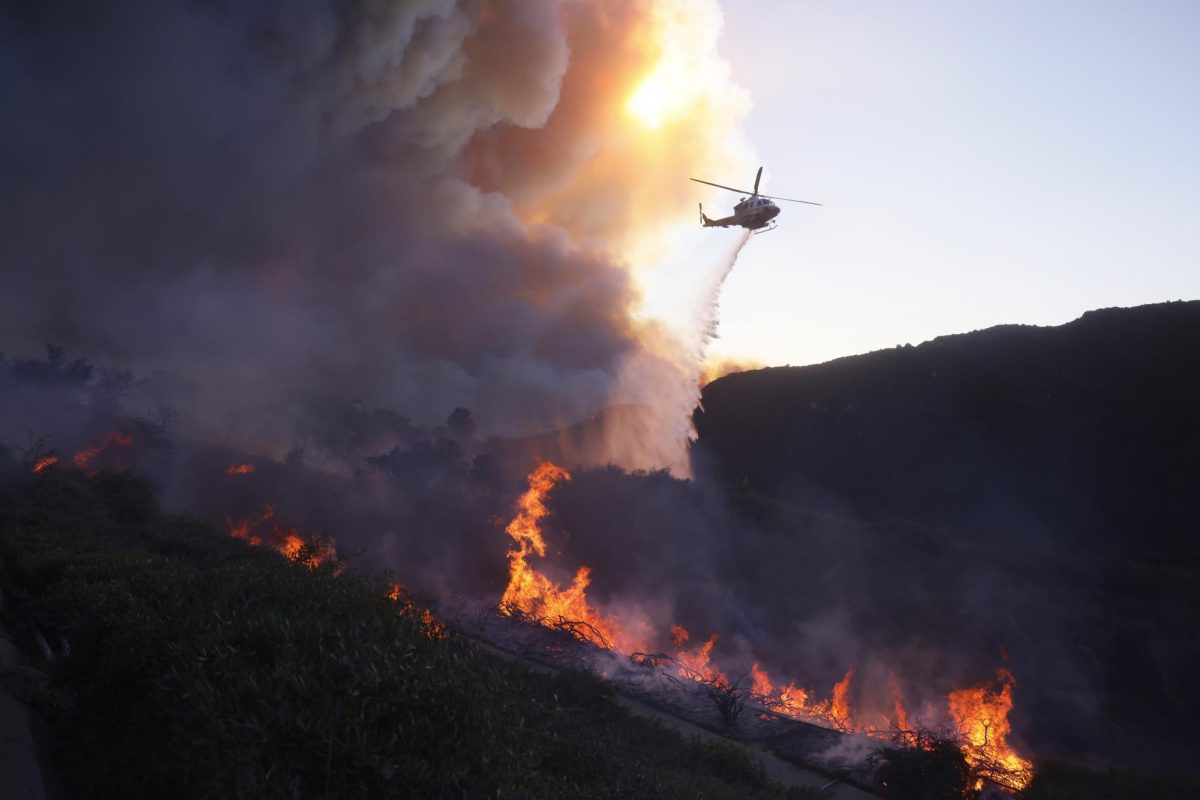 Water is dropped by helicopter on the advancing Palisades Fire in the Pacific Palisades neighborhood of Los Angeles, Tuesday, Jan. 7, 2025.