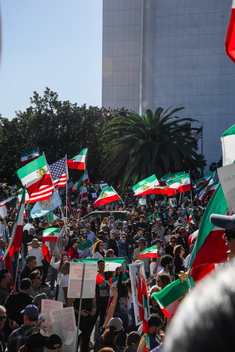 A crowd of demonstrators waves Iranian and American flags during a protest in Westwood, showing solidarity with protesters in Iran and calling attention to human rights abuses by the Iranian government.