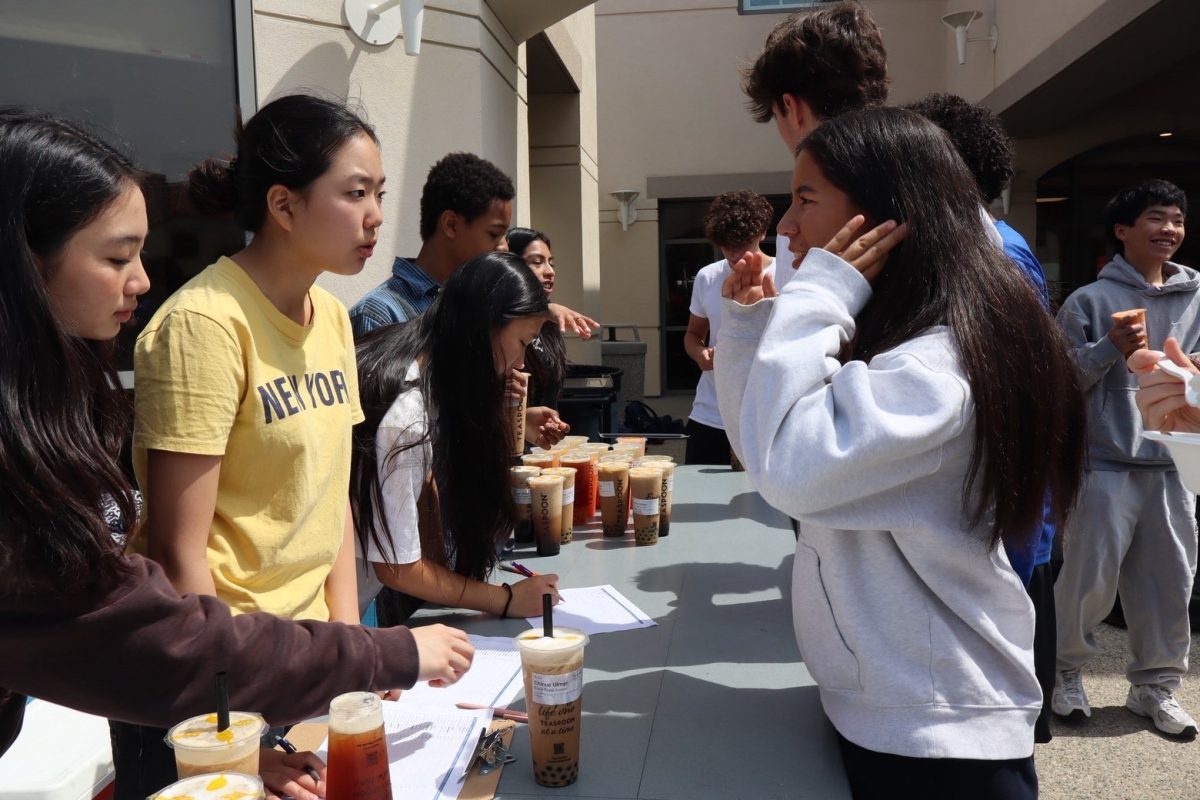 Members of the Hands in Action Club distribute boba drinks to students.